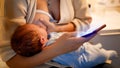 Closeup of young woman using smartphone and browsing internet while feeding her newborn baby son with breast milk at Royalty Free Stock Photo