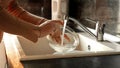 Closeup of young woman washing dishes in kitchen sink. Housewife working, domestic chores, doing housework Royalty Free Stock Photo