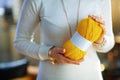 Closeup on young woman holding yellow knitting yarn hunk
