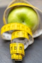 Closeupp shot of a yellow measuring tape around a green apple - healthy lifestyle concept Royalty Free Stock Photo