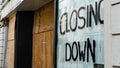 Closing down sign in a boarded-up shop window Royalty Free Stock Photo