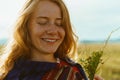 closing her eyes and smiling tenderly holding in his hand a bouquet of red-haired girl with freckles on her face Royalty Free Stock Photo