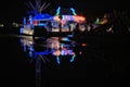 Last ride to close. An illuminated fairground ride is reflected in a large puddle. Surrey, England. Royalty Free Stock Photo