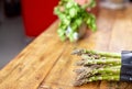 Closue-up image of a bunch of fresh green asparagus in the kitchen on wooden table. Cooking at home concept