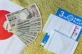 Cloth masks, leaflet and 100,000 yen in cash on Japan flag and a golden paper.