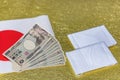 Cloth masks and 100,000 yen in cash sent by govt to fight COVID-19 on Japan flag and golden background.