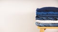 Clothes Concept. Stack of Clothing on Wooden bench by the White Wall. Blue Navy