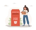 Clothes donation. Woman with cardboard box gives things for recycling or donated. Clothing bin or recycle container