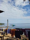 Clothes drying behind the house with a background of traditional boats above the calm sea and clear blue sky. Royalty Free Stock Photo