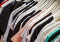 Clothes made of multicolored fabrics and textiles hanging on hangers in a clothing store