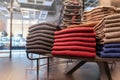 Clothes are neatly stacked on the shelves in the store. pullovers, sweaters warm of different colors are plain. red and