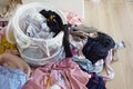 Clothes pile next to laundry basket filled with garments, on hardwood floor Royalty Free Stock Photo