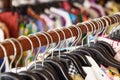 Clothes racks with hangers and with colorful clothes on a blurred background inside shop.