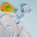 Clothes and rattle for newborn boy. Baby goods on blue background. Royalty Free Stock Photo