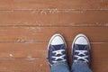 Clothes, shoes and accessories - legs put in gumshoes and blue jeans top view wooden background