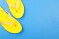 Clothes, shoes and accessories - top view yellow pair flip flops blue background