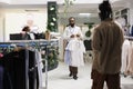 Clothes store worker carrying shirts for customer to try