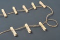 Clothesline with eight wooden clothespins and rope on background of dark concrete