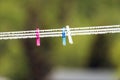 Clothespins outdoors on a string with fresh raindrops after rainy weather with green blurry background Royalty Free Stock Photo