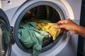 Clothing care a mans hand drops clothes into the washing machine