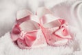 Clothing for newborn. A pair of cute baby pink shoes with a bow for girls on a white bed. Royalty Free Stock Photo