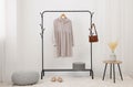 Clothing rack with stylish dress, bag and shoes in room Royalty Free Stock Photo