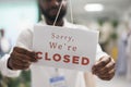 Clothing shop assistant holding sorry we are closed sign Royalty Free Stock Photo