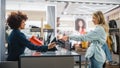 Clothing Store Checkout Cashier Counter: Woman and Male Retail Sales Managers Accept NFC Smartphone Royalty Free Stock Photo