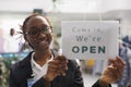 Clothing store smiling woman assistant hanging opening signboard