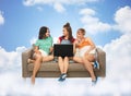 Female friends with laptop computer over clouds Royalty Free Stock Photo