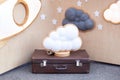 Cloud lamp on suitcase on background of wooden wall with stars. Modern home decoration. Decorative cloud with lamp. Cloud-shaped L