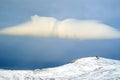 Cloud over a snowy peak in a blue sky Royalty Free Stock Photo