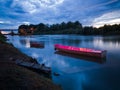 Cloud overcast evening during blue hour. Landscape with Sava river, moored fishing boats near wooden dock and bridge