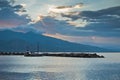 Cloud reflections in a water of aegean sea at sunrise, Volos harbor with Pelion mountain in background