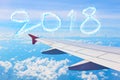 Cloud shape number 2018 years over wing airplane on the blue sky