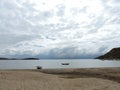 Clouded view to a Lake beach in Bolivia with boats in front