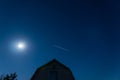 Cloudless, blue, summer night. Starlink`s sputnic fly over the house against the moon Royalty Free Stock Photo