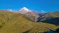 Gergeti Glacier - A cloudless view on Mount Kazbeg in Caucasus, Georgia. There are lush pastures and green hills Royalty Free Stock Photo