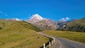 Gergeti Glacier - A cloudless view on Mount Kazbeg in Caucasus, Georgia. There are lush pastures and green hills Royalty Free Stock Photo