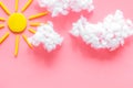 Cloudly weather concept. Sun and clouds on pink background top view space for text