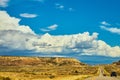 Clouds and blue sky above desert mountains and highway with tourist cars Royalty Free Stock Photo