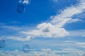 Clouds in the blue sky with bokeh floating soap bubbles in the foreground Royalty Free Stock Photo