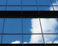 Clouds and bright blue sky reflected in the square mirrored windows of a modern commercial office building Royalty Free Stock Photo