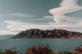 clouds with curious shapes over a range of impressive rocky mountains on the shores of the great blue lake in a quiet Royalty Free Stock Photo