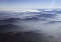 Clouds linger over hills stretching into distance, as photographed from airplane window flying over Chile