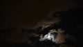 The moon shines brightly in the night sky through the clouds