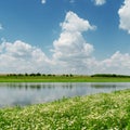Clouds over river and meadow with chamomiles Royalty Free Stock Photo