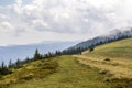 Clouds over top of a mountain with green pine forest and grass m Royalty Free Stock Photo