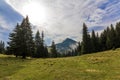 Clouds over top of a mountain with green pine forest and grass m Royalty Free Stock Photo