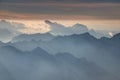 Clouds and peaks rise above jagged blue ridges in Julian Alps